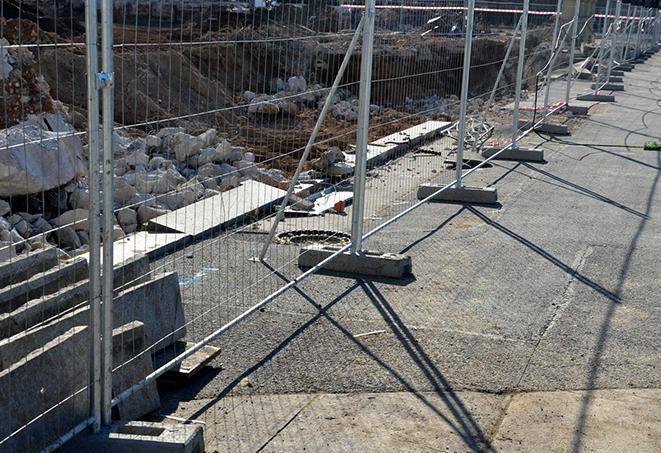 a temporary fence panel gate opening up to a construction site with heavy machinery and equipment